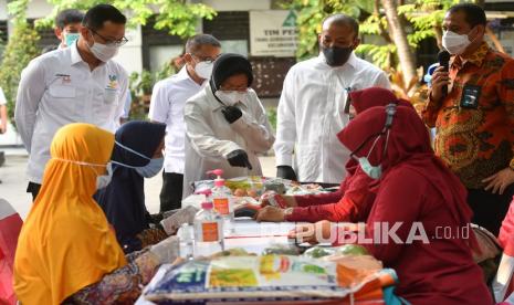 Menteri Sosial Juliari Batubara (kiri) bersama Wali Kota Surabaya Tri Rismaharini (tengah) menyaksikan warga menggunakan Kartu Keluarga Sejahtera saat berbelanja kebutuhan pokok di sela-sela peluncuran bantuan sosial beras bagi Keluarga Penerima Manfaat Program Keluarga Harapan (KPM PKH) di Surabaya, Jawa TImur, Rabu (7/10/2020). Bantuan sosial beras untuk 10 juta KPM PKH tersebut diharapkan dapat mengurangi beban pengeluaran KPM PKH melalui pemenuhan sebagian kebutuhan pangan beras selama pandemi COVID-19.