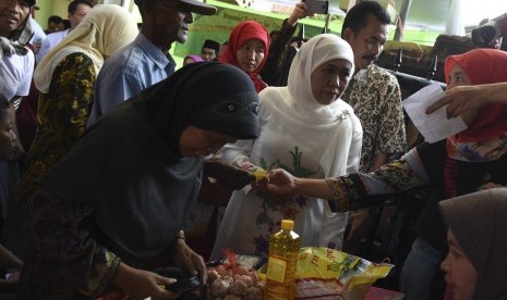 Menteri Sosial Khofifah Indar Parawansa (tengah) menyaksikan proses penukaran kupon sembako murah saat digelar pasar murah Mensos di Surabaya, Jawa Timur, Minggu (26/6). 