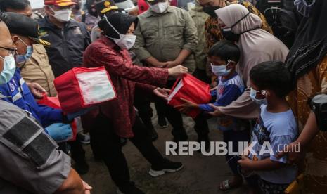 Menteri Sosial Tri Rismaharini (kiri) menyerahkan bantuan sosial kepada warga saat kunjungan kerja di dapur umum korban banjir di Jalan Anoi, Palangkaraya, Kalimantan Tengah, Kamis(15/9).