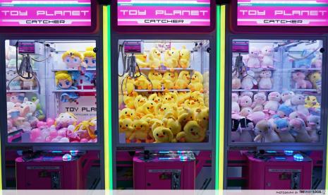 Mesin permainan capit boneka (claw machine). 