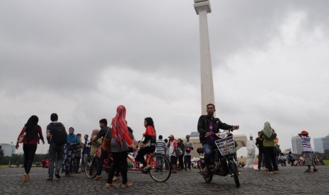   Meski hujan, banyak warga yang mengisi waktu libur dengan berwisata ke kawasan Monumen Nasional (Monas), Jakarta, Kamis (19/2).  (foto : MgROL_34)