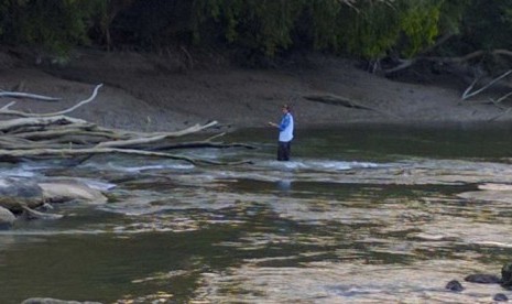 Meski telah ada peringatan soal buaya, seorang nelayan tetap menyebrang sungai.