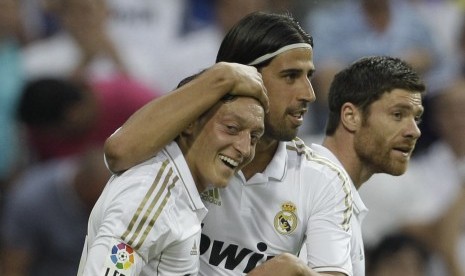 Mesut Ozil (kiri) mendapat ucapan selamat dari Sami Khedira (tengah) usai mencetak gol saat Real Madrid melumat Real Mallorca di laga terakhir La Liga 2011/2012 di Stadion Santiago Bernabeu, Madrid, Ahad (13/5). 