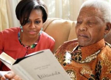 Michelle Obama bersama mantan presiden Afrika Selatan, Nelson Mandela, tengah membaca buku berjudul Nelson Mandela by Himself di kediaman Mandela, Johannesburg