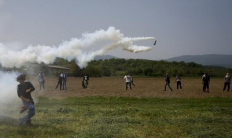 Migran melempar kembali gas air mata saat bentrok dengan polisi di kamp pengungsi di perbatasan Yunani-Makedonia dekat Desa Idomeni, Yunani, Jumat, 13 April 2016.