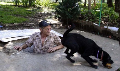 Miguel Restrepo bermain dengan Blackie anjingnya di rumah selokan di kota Medelline,Kolombia, Selasa (4/12).