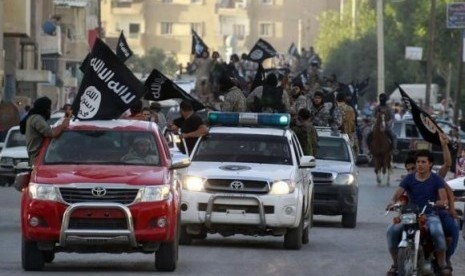 Militant Islamist fighters waving flags, travel in vehicles as they take part in a military parade along the streets of Syria's northern Raqqa province June 30, 2014.