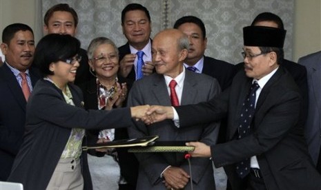 Miriam Coronel-Ferrer chairperson of Philippine Government Peace Panel (front left) exchanges signed document with Mohagher Iqbal chief negotiator for the Moro National Liberation Front (front right), witnessed by Malaysian facilitator Abdul Ghafar Tengku 