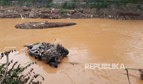 Mobil Daihatsu Xenia terbawa aliran sungai Cipamokolan saat banjir trrjadi di Kota Bandung, Selasa (20/3) kemarin. Petugas masih berusaha mengabgkat bangkai mobil.