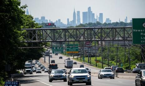 Mobil melaju di sepanjang jalan raya selama akhir pekan Memorial Day sementara New York Skyline dan Empire State Building terlihat di latar belakang di Clifton, New Jersey, AS, 24 Mei 2024.