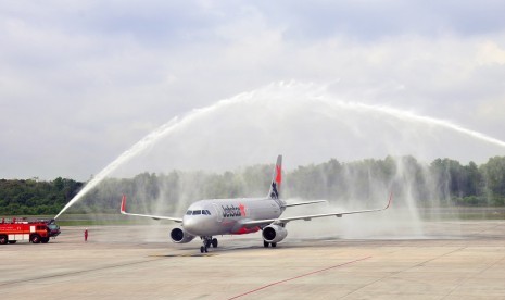 Mobil pemadam kebakaran menyemprotkan air untuk menyambut penerbangan perdana pesawat Jetstar di Bandara Sultan Syarif Kasim II, Pekanbaru, Riau