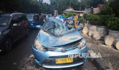 Mobil taksi dengan nopol B 1606 TTC ringsek tertimpa pohon di Jalan Fachrudin, Tanah Abang, Jakarta Pusat, Selasa (30/8).  (Republika/Agung Supriyanto)