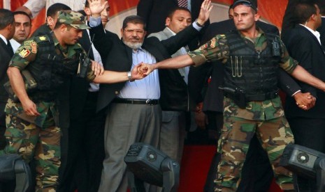 Mohamed Mursi (tengah) melambaikan tangan ke para pendukungnya saat ditahan oleh anggota keamanan presiden di Tahrir Square, Kairo, Mesir, pada 29 Juni 2012. (file foto). 