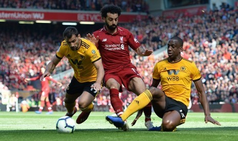 Mohamed Salah berebut bola dengan pemain Wolves dalam pertandingan di Stadion Anfield, Ahad (12/5)