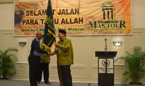 Mohammad Rocky Masyhur, pimpinan Maktour menyerahkan bendera Maktour pada pembimbing Maktour Ustaz Hafiz dan Ustaz Faishol Muzammil