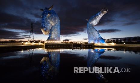 Monumen sosio-historis Kelpies menyala dengan warna biru sebagai penghargaan untuk menghormati Sistem Kesehatan Nasional (NHS) dan pekerja perawatan, di Falkirk, Skotlandia, Senin (30/3). Menurut laporan berita, patung kuda setinggi 30 meter akan menjadi diterangi dengan warna biru untuk seluruh periode krisis COVID-19 sebagai penghormatan abadi kepada NHS dan pekerja perawatan sosial, setelah pertunjukan dukungan nasional 26 Maret malam yang membuat penduduk di seluruh Inggris bertepuk tangan untuk mendukung pekerja kesehatan. Patung-patung, yang diciptakan oleh seniman Andy Scott, didirikan pada 2014 di Helix Park dekat perpanjangan Forth dan Clyde Canal. 