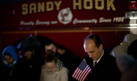 Mourners listen to a memorial service over a loudspeaker outside Newtown High School for the victims of the Sandy Hook Elementary School shooting, Sunday, Dec. 16, 2012, in Newtown, Conn.  