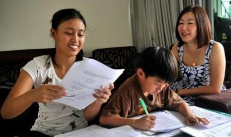 Mrs Eileen Tjandra (right), 42, dengan putranya, Chirstoper, 9, dan PRT Indonesia, Yuli, 26 tahun. Eileen membayar Yuli 520 dolar Singapura sebulan, di atas rata-rata pasar untuk PRT berpengalaman.