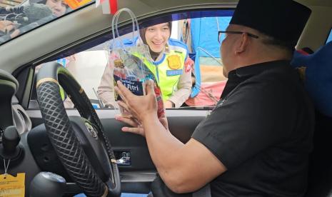 Salah satu polisi wanita Polda Banten menyapa pemudik di Dermaga Eksekutif Pelabuhan Merak, Cilegon, Banten pada Jumat (5/4/2024).