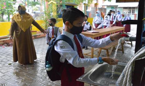 Murid antre mencuci tangan sebelum memasuki ruangan belajar di Sekolah Dasar, Senin (11/1). 