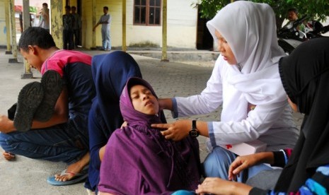 Murid sekolah membantu mengobati temannya yang terluka saat simulai gempa dan tsunami yang digelar mahasiswa Universitas Syiah Kuala (Unsyiah)