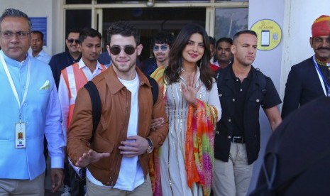 Musisi Nick Jonas (berkacamata hitam) dan aktris Priyanka Chopra tiba di bandara di Jodhpur, Rajashtan, India, (29/11). Keduanya berada di India untuk melangsungkan pernikahan.