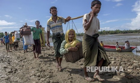 Muslim Rohingya, yang menyeberang dari Myanmar ke Bangladesh, membawa seorang wanita tua masuk dalam keranjang dan berjalan menuju sebuah kamp pengungsi di Shah Porir Dwip, Bangladesh, Kamis, (14/9).