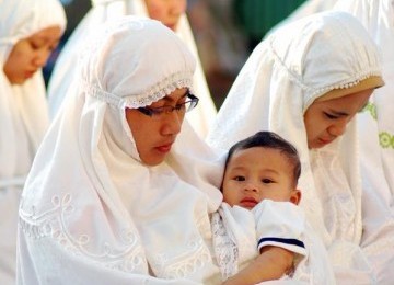 Muslimah shalat sambil gendong anak.