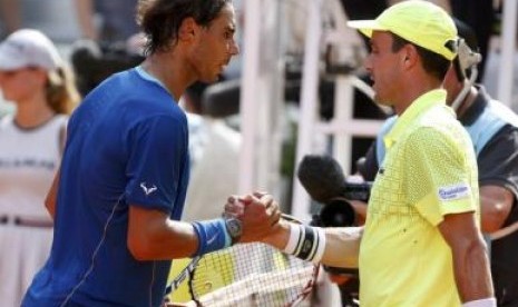 Nadal berbaju biru berjabat tangan dengan Baut setelah memenangkan pertandingan dan maju ke final Madrid Masters.