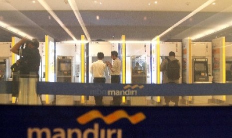 Nasabah melakukan transaksi melalui Anjungan Tunai Mandiri (ATM) Bank Mandiri di Jakarta, Ahad (22/6). 