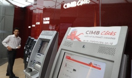 Nasabah mengambil uangnya dari mesin anjungan tunai mandiri (ATM) di salah satu kantor cabang Bank CIMB Niaga, Jakarta, Jumat (21/6). 