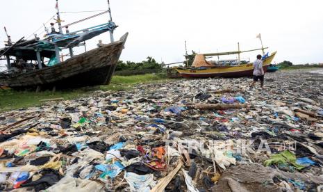 Nelayan beraktivitas di dekat tumpukan sampah yang berserakan di Pantai Dadap, Indramayu, Jawa Barat, Sabtu (15/1/2022). Sampah yang sebagian besar dari limbah rumah tangga dan plastik tersebut terseret arus dan menumpuk di pantai sehingga mengganggu aktivitas nelayan.