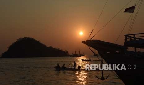 Nelayan melintas saat matahari tenggelam di perairan Labuan Bajo, Manggarai Barat, Nusa Tenggara Timur, Jumat (12/10).