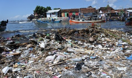 Nelayan melintasi muara sungai yang tercemar sampah plastik di Pantai Satelit, Desa Tembokrejo, Muncar, Banyuwangi, Jawa Timur, Jumat (19/4/2019).