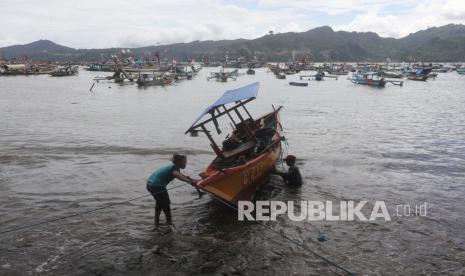 Nelayan membersihkan perahu saat tidak melaut di Pantai Popoh Tulungagung, Jawa Timur, Ahad (6/3/2022). Badan Meteorologi dan Klimatologi (BMKG) memprediksi terjadi gelombang tinggi 2,50 hingga 4,0 meter di perairan selatan Jawa selama sepekan mendatang. 