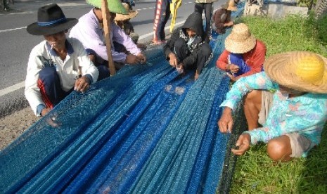 Nelayan memperbaiki jaring pukat harimau, di Jalan Raya Pamekasan-Sampang Desa Bandaran, Tlanakan Pamekasan, Jatim, Selasa (3/2)