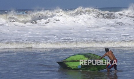 Nelayan mengevakuasi perahu yang terbalik di tepi Pantai Sine, Tulungagung, Jawa Timur, Rabu (25/7).