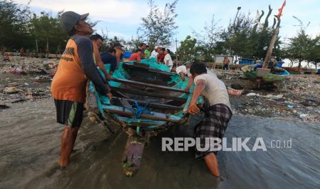 Nelayan mengevakuasi perahunya yang pecah akibat terhantam gelombang laut di pesisir Cumpat, Surabaya, Jawa Timur, Kamis (12/11/2020). Akibat gelombang tinggi disertai angin kencang yang terjadi pada Rabu (11/11) malam di pesisir itu menyebabkan sejumlah perahu nelayan yang ditambatkan rusak dan tenggelam terhantam ombak. 