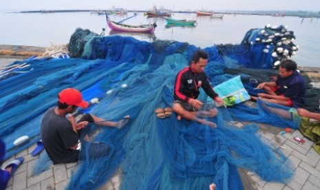 Nelayan yang tidak melaut memperbaiki jaring di Pelabuhan Branta Pesisir, Tlanakan, Pamekasan, Jawa Timur, Selasa (28/11). Sebagian nelayan di daerah itu tidak melaut menyusul peringatan BMKG terkait Badai Siklon Tropis yang meliputi sejumlah daerah di Indonesia termasuk Jawa Timur dengan potensi tinggi gelombang antara 2,5 meter hingga enam meter.