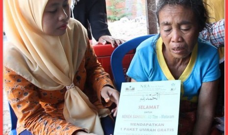 Nenek  Sahnun (kanan) menerima voucher hadiah umrah gratis yang diserahkan oleh staf NRA Mataram.