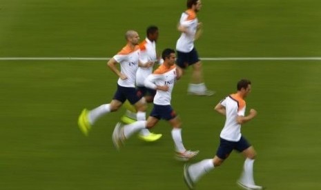 Netherlands' Robin Van Persie (center) and Ron Vlaar (left) run with teammates during a training session in Rio de Janeiro June 19, 2014.