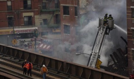 New York City firefighters examine the rubble at an apparent building explosion fire and collapse in the Harlem section of New York, March 12, 2014.