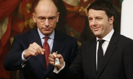 Newly appointed Italian Prime Minister Matteo Renzi (right) rings a silver bell to signify the start of his first cabinet meeting, next his predecessor Enrico Letta, at Chigi Palace in Rome on February 22, 2014. 