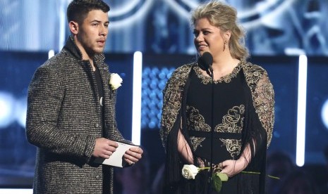 Nick Jonas dan Kelly Clarkson membawa mawar putih saat membacakan nominasi di Grammy Awards, Senin (29/1).