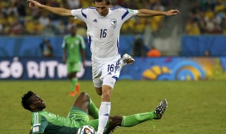 Nigeria's Joseph Yobo falls to the ground as Bosnia's Senad Lulic goes for the ball during their 2014 World Cup Group F soccer match at the Pantanal arena in Cuiaba June 21, 2014.