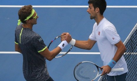 Novac Djokovic (kanan) dan Denis Istomin bersalaman seusai laga babak kedua Australia Terbuka di Rod Laver Arena, Kamis (19/1). Djokovic kalah pada laga yang berlangsung lima set.