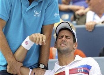 Novak Djokovic (kanan) mengerang kesakitan saat mendapat perawatan dari pelatih Hugo Gravil. 