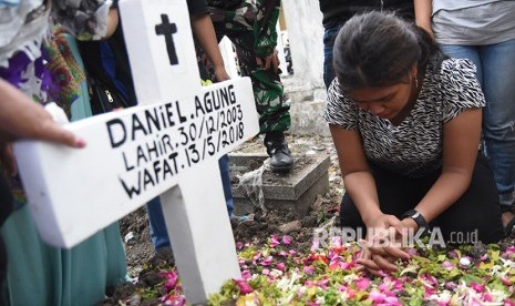 Novi (kanan) kakak dari Daniel Agung Putra Kusuma korban bom bunuh diri di Gereja Pantekosta Pusat Surabaya (GPPS) berada disamping pusara ketika pemakaman di Makam Putat Gede Surabaya, Jawa Timur, Selasa (15/5).