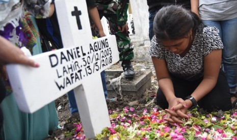 Novi (kanan) kakak dari Daniel Agung Putra Kusuma korban bom bunuh diri di Gereja Pantekosta Pusat Surabaya (GPPS) berada disamping pusara ketika pemakaman di Makam Putat Gede Surabaya, Jawa Timur, Selasa (15/5). 