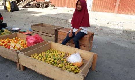 Nur Fainah (13 tahun) yang duduk di bangku sekolah kelas 2 SMP Negeri 5 Kabupaten Sigi sedang membantu ibunya berjualan di Pasar Inpres Manonda di Jalan Kacang Panjang, Kota Palu, Sulawesi Tengah. Fainah salah satu anak korban gempa bumi, impiannya menjadi seorang perancang busana.